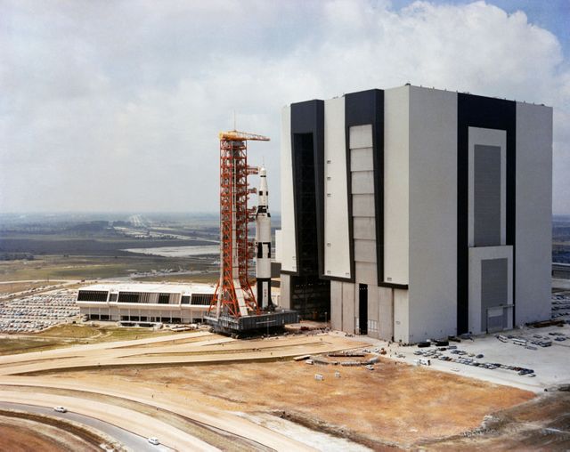 Apollo/Saturn V facilities Test Vehicle on crawler-transporter moving from Vehicle Assembly Building towards Pad A, verifying launch facilities and training launch crews. Useful for educational content, historical articles on space exploration, NASA operations, and showcasing space technology evolution.