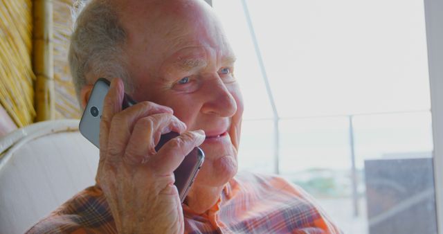 Senior Man Talking on Phone While Sitting Near Window - Download Free Stock Images Pikwizard.com