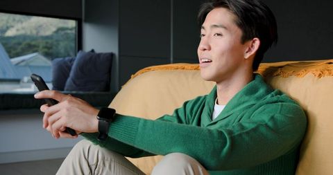 Relaxed Man Enjoys Leisure Time with Remote in Cozy Living Room