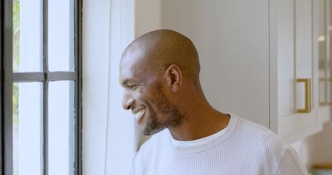 Contemplative Man Looking Out Window with Relaxed Atmosphere