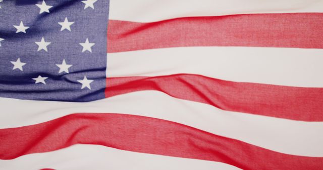 Image depicts a closeup view of the American flag with its distinctive stars and stripes. The flag appears to be gently waving. It is ideal for use in patriotic campaigns, American holidays like Independence Day, Veterans Day, or Memorial Day, and educational materials about the United States. It highlights themes of patriotism, national pride, and freedom.