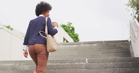 Businesswoman with Coffee Walking Upstairs Outdoors, City Lifestyle