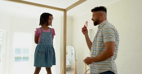Father and daughter bonding in bedroom with heart-shaped toy