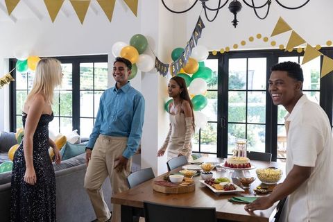 Diverse friends celebrating birthday in elegantly decorated dining room