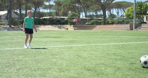 Youth girl practicing soccer on sunny outdoor field during summer training session