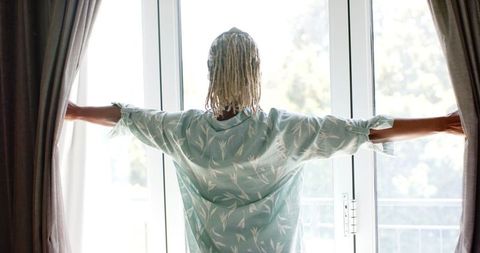 Senior Woman Opening Curtains Welcoming Morning Sun