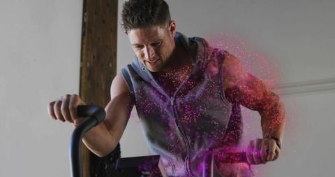 Fit Man Exercising on Stationary Bicycle with Energy Particles