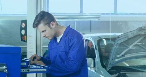 Automotive Technician Inspecting Engine with Tool Cart in Bright Modern Garage