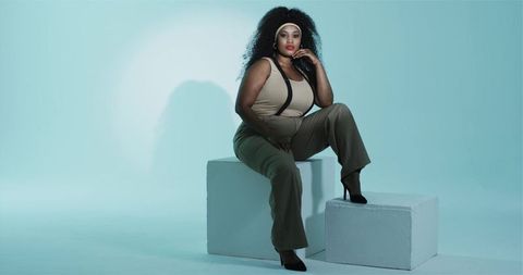 Confident Woman in Olive Green Fashion Posing on White Blocks