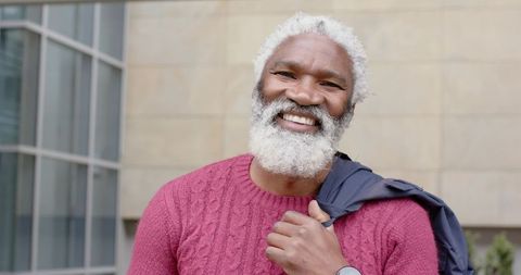Senior african american man smiling in magenta sweater holding jacket urban portrait