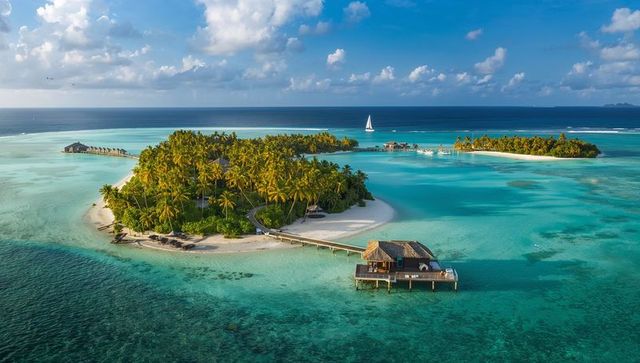 Tropical atoll resort with overwater bungalow and wooden jetty in turquoise lagoon