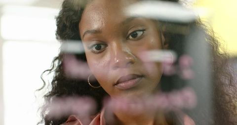 Focused woman analyzing notes on office glass board