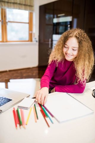 Schoolgirl Drawing with Colored Pencils in Modern Home Kitchen