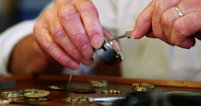 Elderly watchmaker carefully repairing vintage watch parts with detailed precision. Perfect for use in articles on traditional craftsmanship, horology, or showcasing the art of watchmaking. Suitable for blogs on DIY repairs, hobbyist activities, and profiles of artisan skills.
