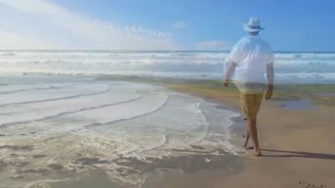 Man Walking Along Sunny Beach Shoreline for Relaxation