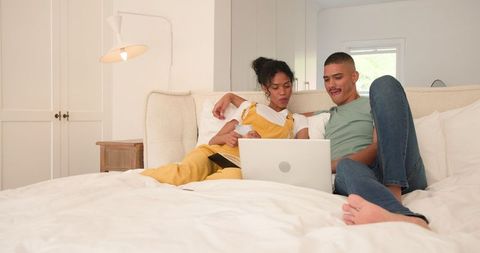 Diverse Couple Watching Laptop Together on Cozy Bed
