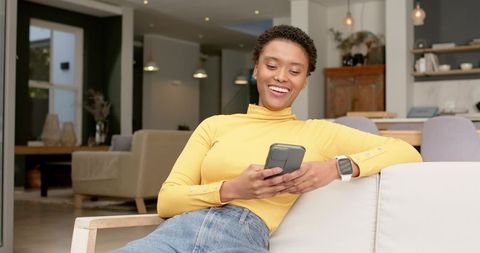Relaxed Woman Sitting and Using Smartphone at Home Comfortably