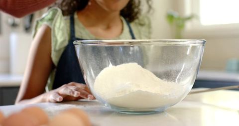 Woman and girl baking together mixing flour in glass bowl home kitchen learning