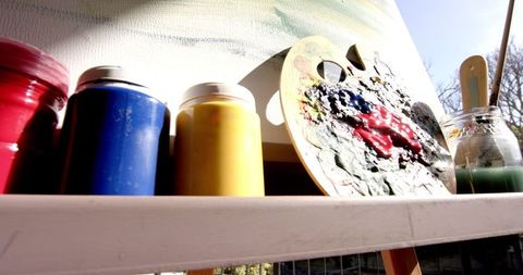 Artistic tools with paint cans and palette in sunlit studio
