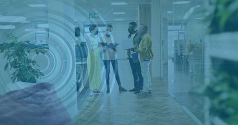 Team standing in modern office corridor discussing documents with tablet HUD overlay