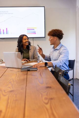 Diverse professionals collaborating in modern conference room with laptop and data charts