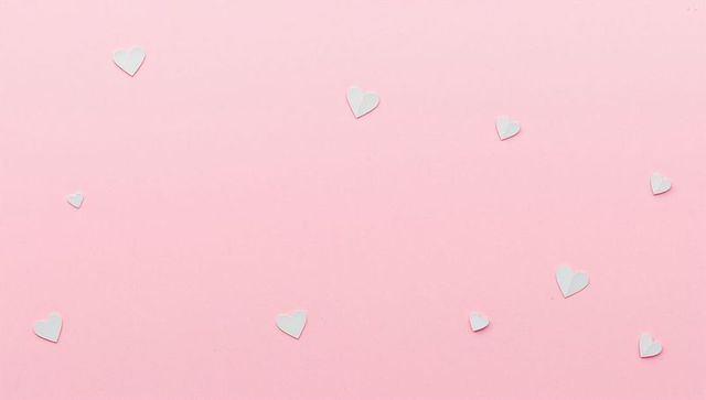 White paper hearts lying on pink pastel background scattering soft shadows minimal flatlay