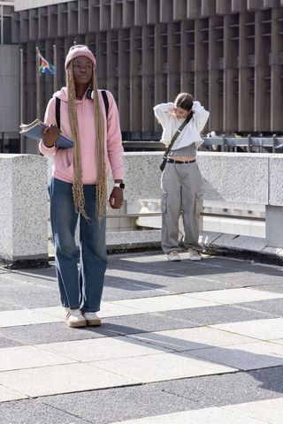 Diverse young women standing on urban rooftop terrace holding notebooks and backpacks