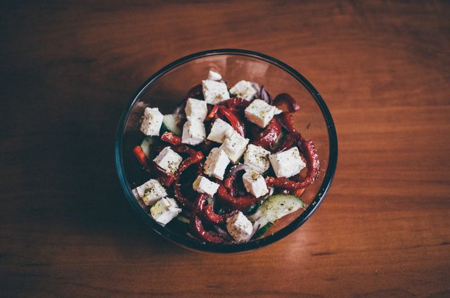 This healthy vegetable salad features fresh feta cheese cubes, presented in a glass bowl. It is perfect for concepts related to healthy eating, vegetarian diets, and fresh ingredients. Suitable for use in cookbooks, health articles, nutritional blogs, and restaurant menus.