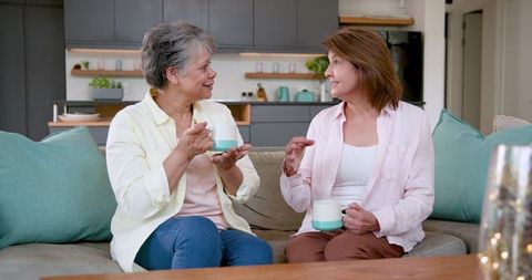 Senior Asian Mother and Daughter Sitting on Sofa at Home