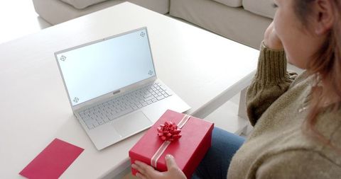 Woman Holding Gift During Online Video Call on Laptop