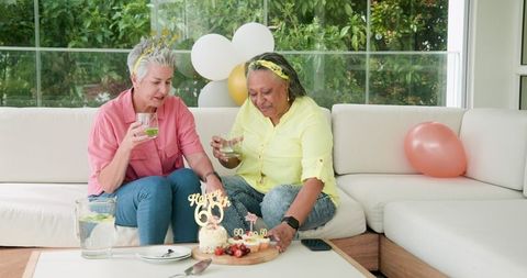 Joyful senior couple celebrating birthday with drinks in lounge area