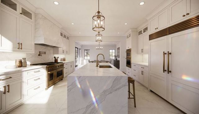 Waterfall marble island with brass faucet in luxury open-plan kitchen with white cabinetry