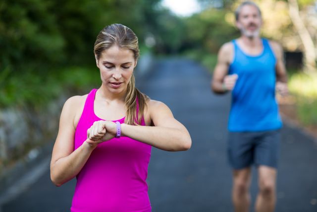 Fit woman checking time on wristwatch after jogging