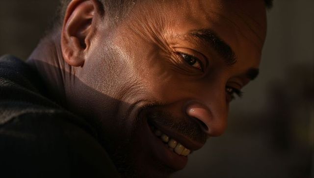 Smiling african american man turning head, warm close-up showing textured skin and gaze
