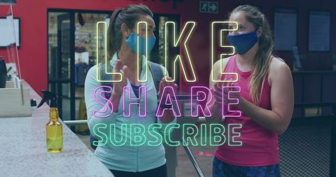 Two women wearing masks disinfecting hands in fitness center