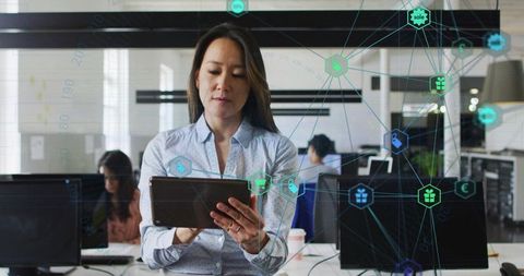 Businesswoman holding tablet in modern office with network overlay for digital collaboration