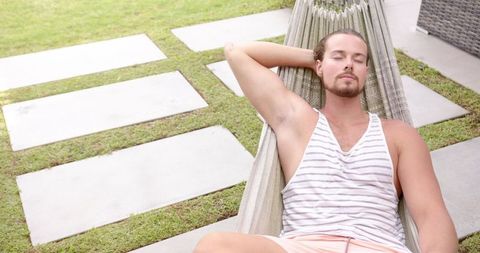 Young Man Relaxing Outdoors on Hammock on a Bright Summer Day