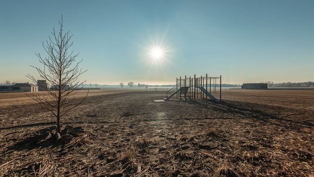 Abandoned playground in sparse rural landscape during quiet sunlit morning