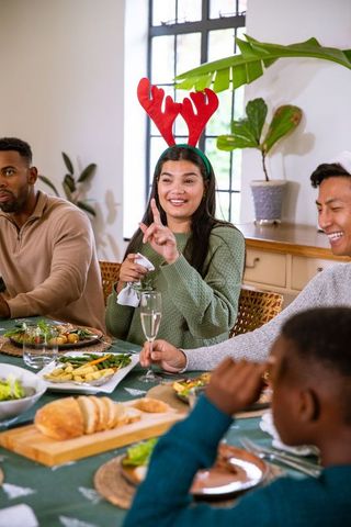 Diverse family enjoys celebratory meal with festive antlers