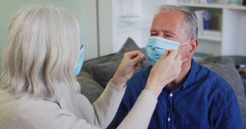 Senior Couple Adjusting Face Masks on Sofa