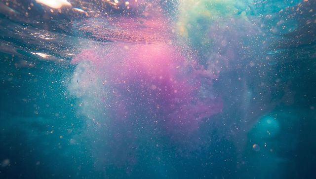 Vibrant pink and purple pigment clouds underwater