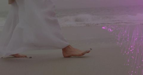 Barefoot woman walking on wet beach in flowing white dress with purple light overlay