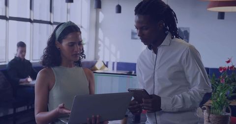 Collaborating over laptop and tablet in sunlit modern coworking lounge for team productivity