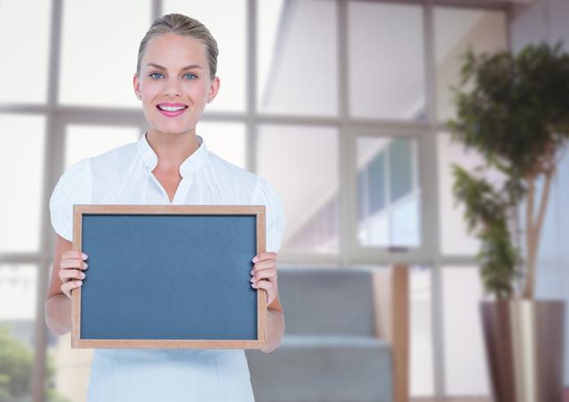 Digital composite of Happy business woman with blackboard in the hall of the office