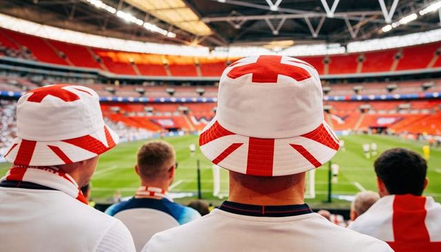 England fans wearing union jack bucket hats watching football match in stadium crowd