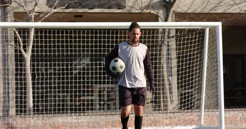 Soccer Player Walking Near Goalpost on Sunny Day