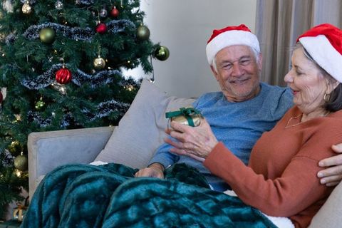 Senior couple exchanging holiday gift by christmas tree