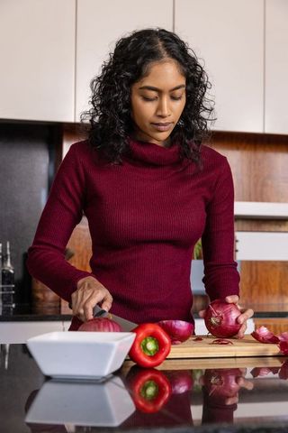 Focused Woman Slicing Onion in Modern Kitchen