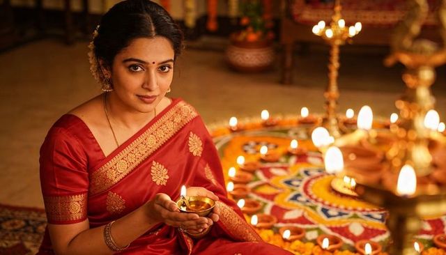 Indian woman lighting diya for diwali in red silk saree with rangoli and oil lamps