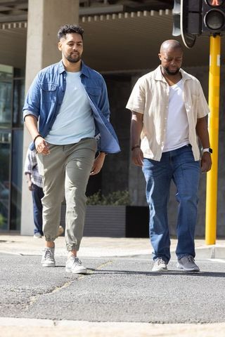 Two african men walking across downtown crosswalk in casual clothes and smartwatch